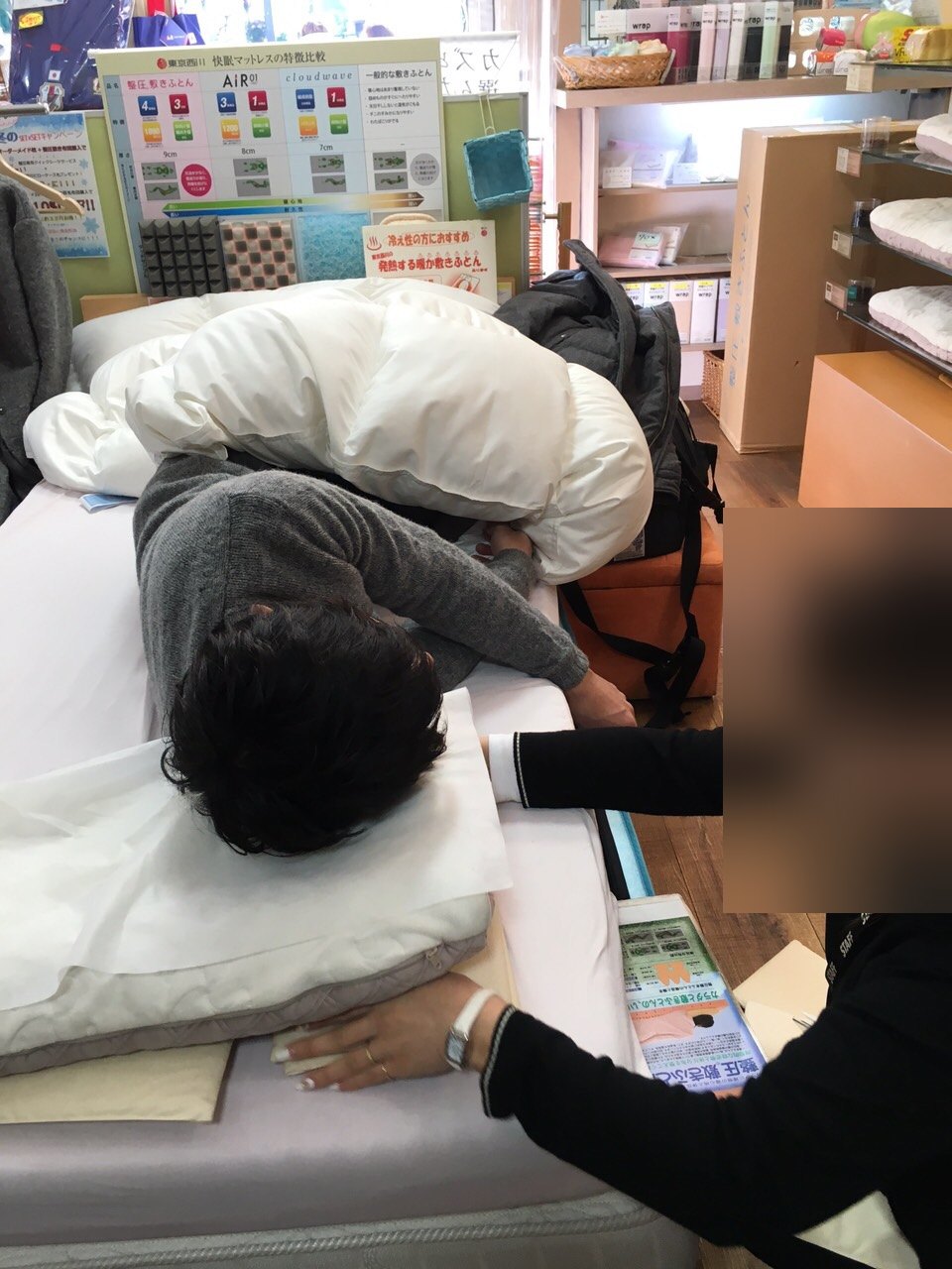 横向きに寝ている客の枕に店員が手を当てて、高さを直しているところ